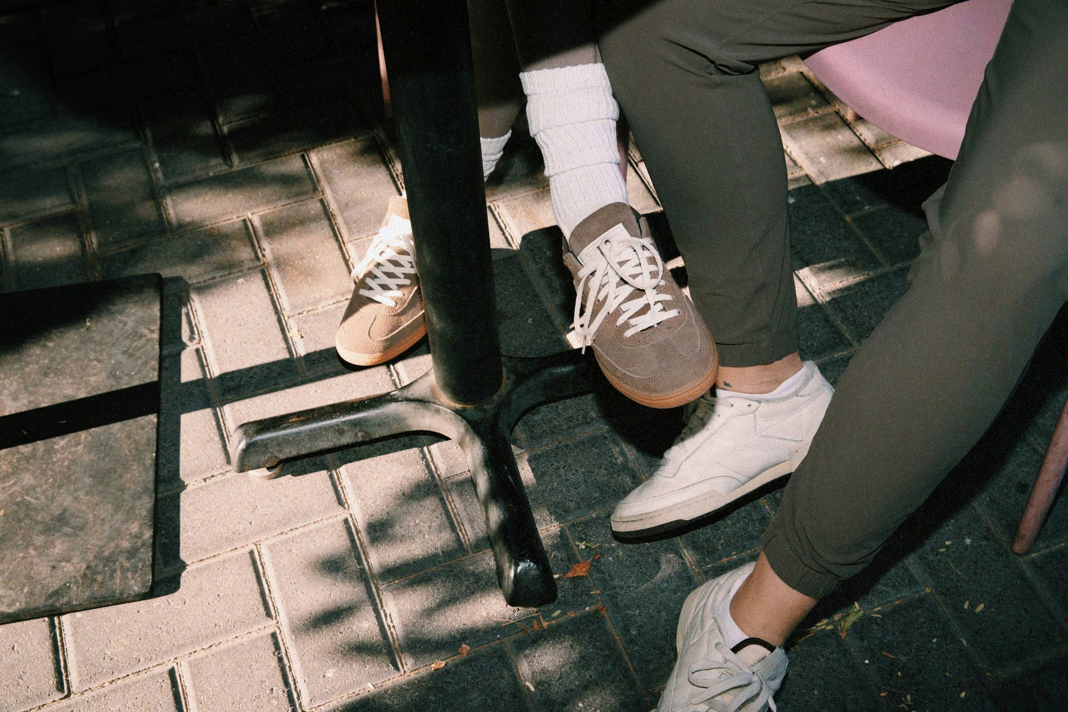 Two people sitting at cafe table wearing casual sneakers