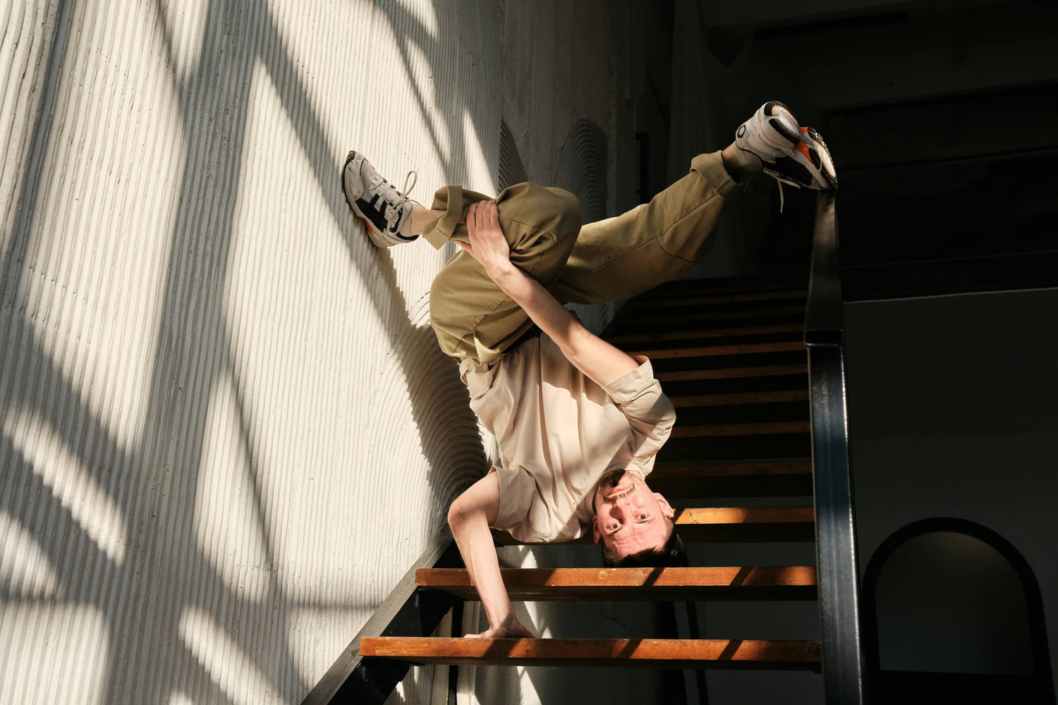 Man performing breakdance move upside down on staircase