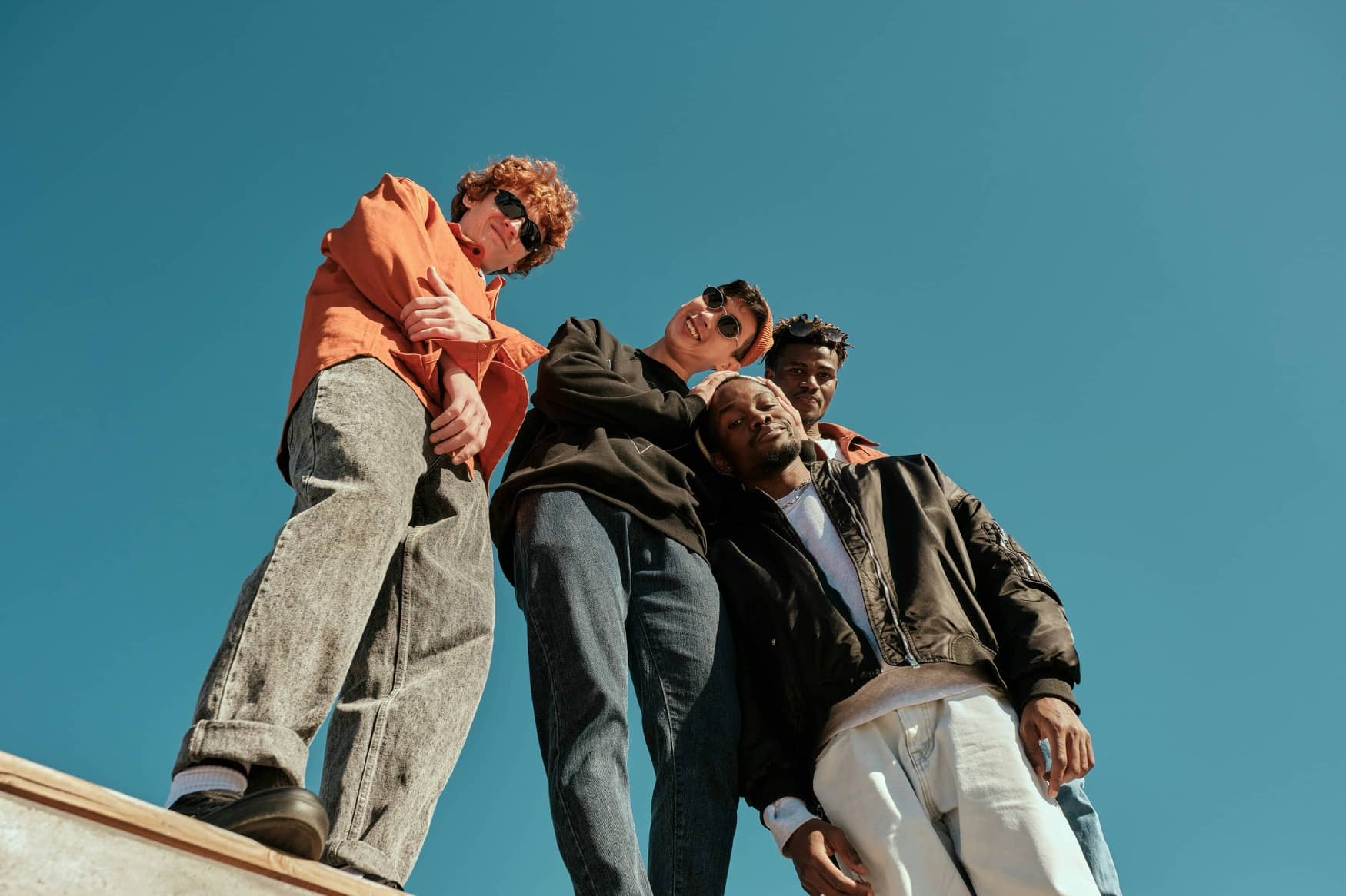 Four people standing on a rooftop against a clear blue sky