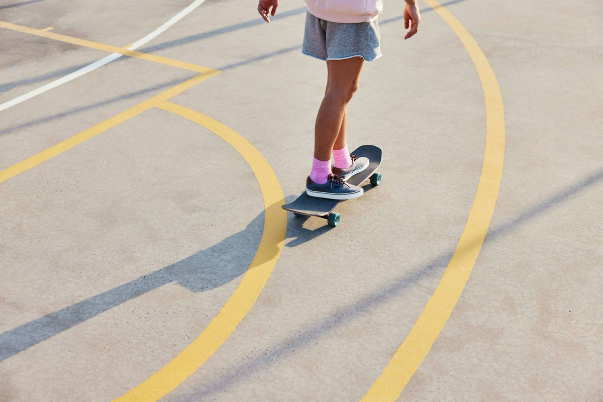 Person skateboarding on outdoor court wearing pink socks and sneakers
