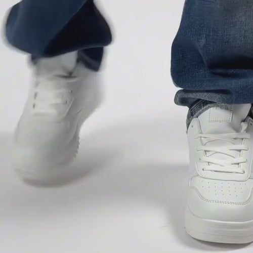 Close-up of white sneakers paired with blue jeans