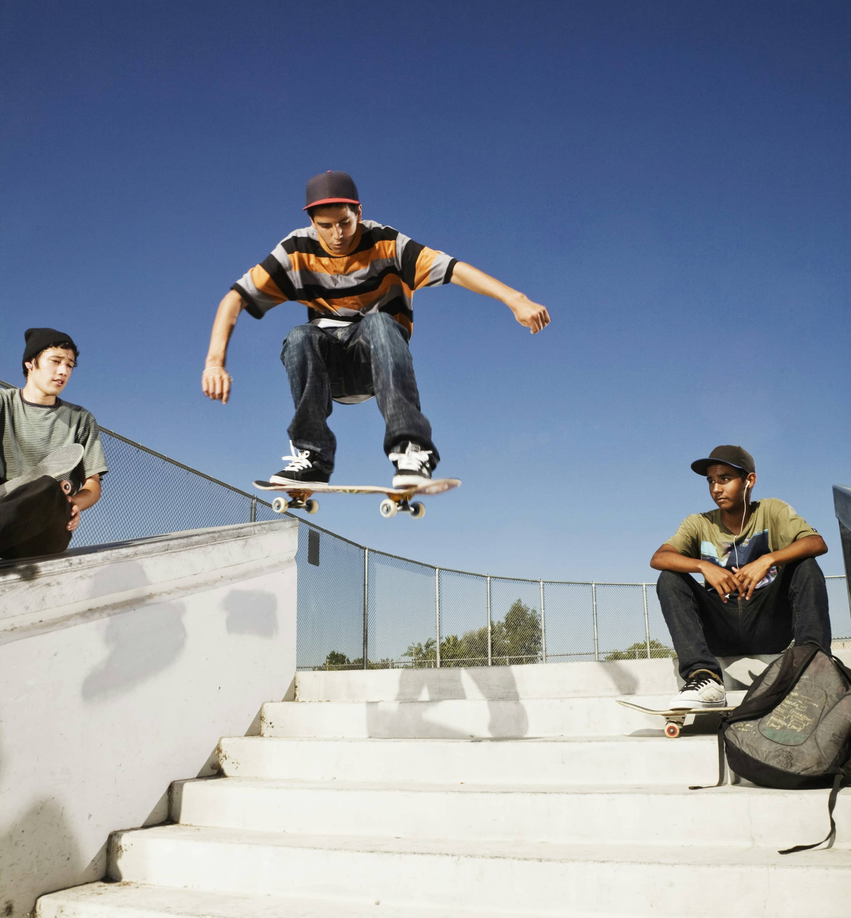 Skateboarder performing a trick on stairs with two others watching